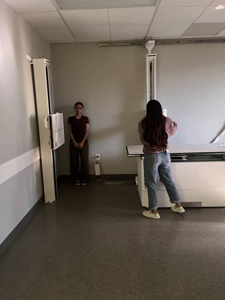 Instructor explaining exposure settings beside X-ray console